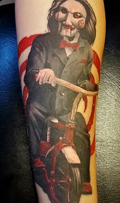 a tattoo with a clown riding a motorcycle on it's arm and holding a cane