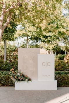 a white monument sitting in the middle of a park filled with trees and flowers on top of it