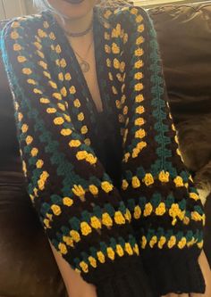 a woman is wearing a crocheted scarf with flowers on the sides and arms