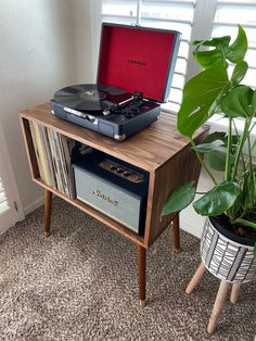 a record player sitting on top of a wooden table next to a potted plant