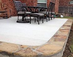 an outdoor patio with chairs and tables on it's concrete slab, in front of a brick building