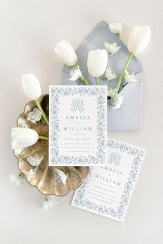 the wedding stationery is laid out on top of an envelope and some white tulips