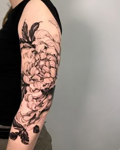 a woman with a black and white flower tattoo on her arm, showing the flowers