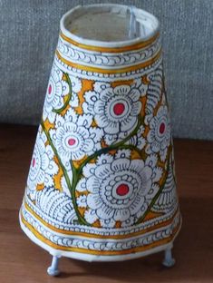 a white and yellow vase sitting on top of a wooden table