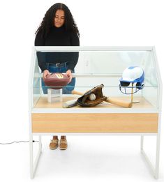 a woman standing behind a display case with baseball equipment