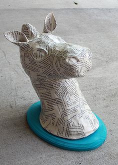 a paper mache giraffe sitting on top of a blue object in the street