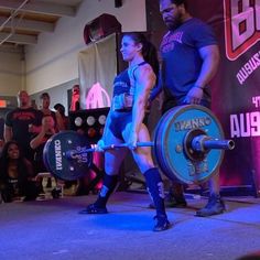 a man and woman are performing a competition with barbells