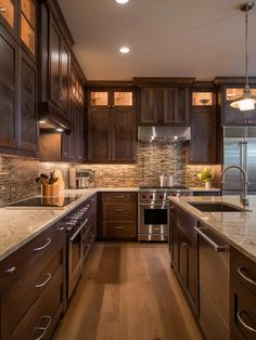 a kitchen with dark wood cabinets and marble counter tops, along with stainless steel appliances