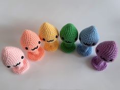 crocheted stuffed animals are arranged in a row on a white surface, with one being an octopus and the other is smiling