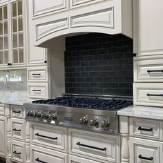 a stove top oven sitting inside of a kitchen next to white cabinets and counter tops