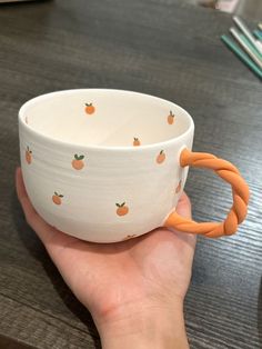 a hand holding a white bowl with orange handles and an orange rubber band around it