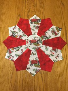 a red and white quilted christmas ornament sitting on top of a wooden table