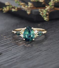 a green ring sitting on top of a wooden table next to a branch with leaves