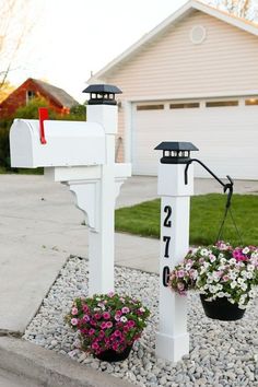 two mailboxes with flowers in front of a house