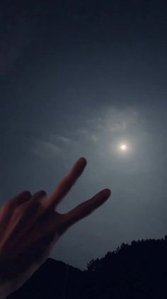 a person's hand with the moon in the background