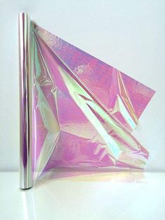 an origami paper airplane sitting on top of a white table next to a metal pole