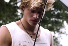 a young man holding an umbrella in front of his face and wearing a white tank top