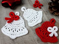 three crocheted christmas decorations on a wooden table next to a red ornament