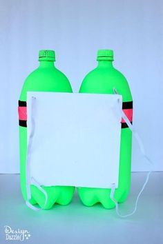 two green plastic bottles holding a white sign