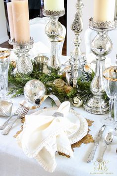 a white table topped with silver candles and plates