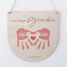 a wooden sign hanging on the wall that says, my heart belongs to grandma with two hands