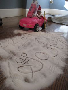 a child is sitting in a pink toy car on the floor with words written all over it