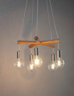 three light fixtures hanging from a wooden beam with four bulbs on each end and one bulb down