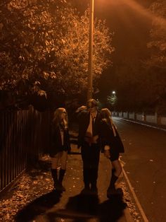 three people walking down the street at night