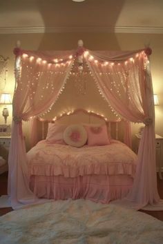 a pink bed with lights on the headboard and canopy over it, in a bedroom