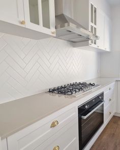 a stove top oven sitting inside of a kitchen next to white cupboards and drawers