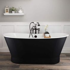 a black and white bathtub with an antique faucet next to it on a wooden floor