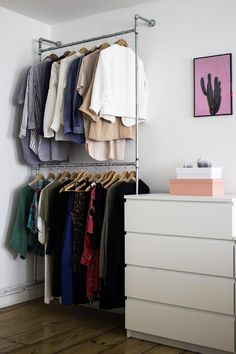 an organized closet with clothes hanging on the rails and drawers in front of a dresser