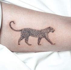 a tattoo on the arm of a woman with a cheetah walking across it