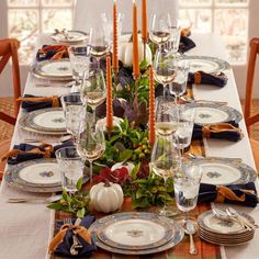 a dining table set with place settings, plates and candles for thanksgiving or fall dinner