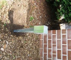 a garden tool laying on the ground in front of a brick wall and shrubbery