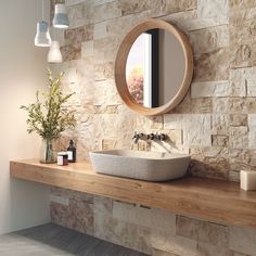 a bathroom with stone walls and a round mirror on the wall, along with a sink