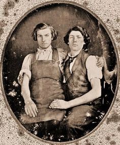 an old photo of two men in aprons sitting next to each other with their arms around one another