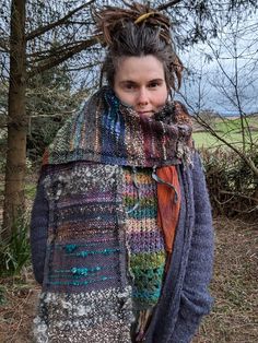 a woman with dreadlocks wearing a multicolored knitted sweater and scarf