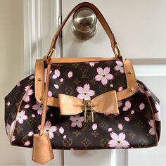 This Ultra-Rare Louis Vuitton Cherry Blossom Sac Retro Bag Is A Coveted Piece From The Exclusive 2003 Collection, Designed By The Iconic Duo Takashi Murakami And Marc Jacobs. Celebrated For Its Timeless Elegance And Feminine Charm, This Collectible Bag Perfectly Captures Vintage Flair With Its Exquisite Hardware, Including Beautiful Studs, A Signature Padlock, And An Eye-Catching Bow Detail. Product Details: Style: Louis Vuitton Top Handle Bag Collection: 2003, Designed By Marc Jacobs Material: Brown Coated Canvas With Floral Monogram Cherry Blossom Print Hardware: Brass Trim: Leather Interior: Alcantara Lining With Single Interior Pocket Features: Flat Handle With A 4 Louis Vuitton Cherry Blossom, Louis Vuitton Top, Iconic Duo, Dream Bag, Cherry Blossom Print, Brass Trim, Louis Vuitton Limited Edition, Retro Bags, Tv Fashion