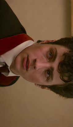 a young man wearing a red and white shirt is looking at the camera with an intense look on his face