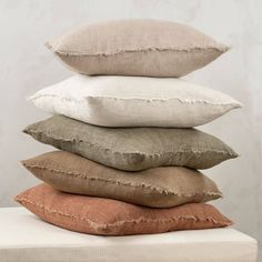 four pillows stacked on top of each other in different colors and sizes, with the same pillow