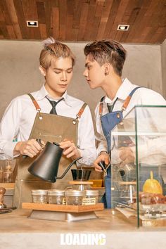 two young men standing next to each other in front of a counter with pots and pans on it