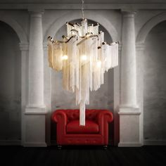 a chandelier hanging from the ceiling in a room with a red chair and white columns