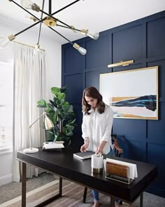 a woman standing at a desk with a laptop