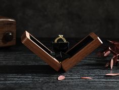 a wooden box with a ring in it on a table next to leaves and flowers