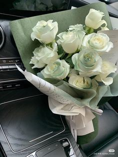 a bouquet of white roses sitting on top of a car dashboard