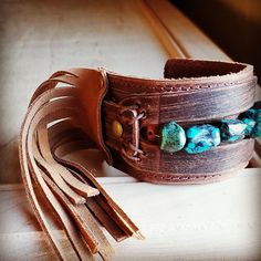 Distressed Finish Leather Cuff features a genuine strand of chunky African Turquoise. Each strand is different and will show varying shades of the natural stone. ***Please view all the pictures as they show examples of the many stone colors Cuff measures 2" by 9" in length Adjustable to 7" and 7.5" Although your item will resemble the photo, each piece is created by hand, so no two are identical.Thank you for visiting The Jewelry Junkie! Adjustable Turquoise Leather Bracelet In Rustic Style, Adjustable Rustic Turquoise Leather Bracelet, Bohemian Turquoise Cuff Bracelet With Patina, Turquoise Bohemian Cuff Bracelet With Patina, Adjustable Turquoise Bracelets With Patina, Adjustable Turquoise Cuff Bracelet For Festivals, Adjustable Turquoise Bracelet With Patina, Bohemian Cuff Bracelet With Patina, Bohemian Brown Cuff Bracelet With Patina