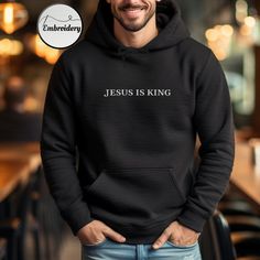 Embroidered Jesus Is King Hoodie  High-quality embroidery - Made from premium materials, this pullover hoodie ensures both warmth and comfort. The classic design makes it a versatile addition to your Christian wardrobe. Christian Hoodie Features: * 50% pre-shrunk cotton, 50% polyester * Double-lined hood with matching drawcord * Front pouch pocket * High quality embroidery with Bible verse * Available in a range of sizes and colors, it's suitable for both men and women. Christian Clothing: I love adorning shirts with scripture, as it helps spread the message of the Good News of Christ. Each Bible verse woven into fabric has the power to convey profound truths, speaking to anyone who encounters them. This hooded sweatshirt is made especially for you as soon as you place an order, which is w Hooded Embroidered Sweatshirt For Winter, Embroidered Hooded Sweatshirt For Winter, Cotton Hoodie With Embroidered Graphics, Hooded Winter Sweatshirt With Embroidered Graphics, Winter Hooded Sweatshirt With Embroidered Graphics, Embroidered Long Sleeve Hoodie For Streetwear, Black Embroidered Hooded Hoodie, Fleece Hoodie Sweatshirt With Embroidered Graphics, Fleece Hoodie Sweatshirt With Letter Embroidery