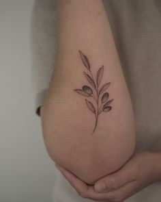 a woman holding her stomach with a tattoo on it's side, showing the small leaves