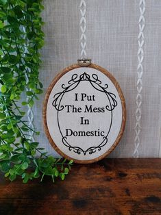 i put the mess in domestic cross stitch pattern on wooden hoop frame with green plant